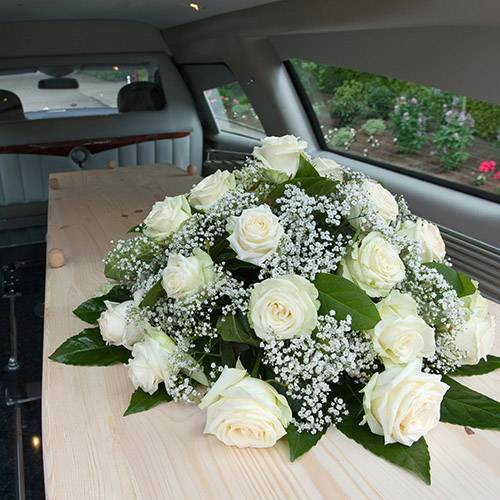 coffin with floral display in back of hearse