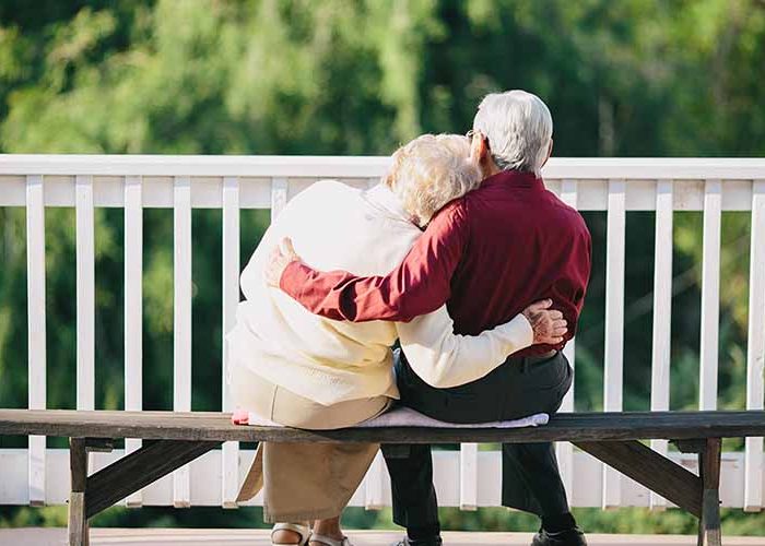 happy old couple sat on a bench happy old couple sat on a bench